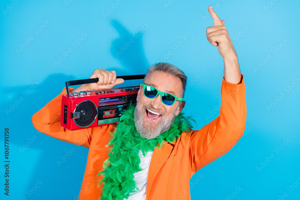 Photo of trendy eccentric man carry boombox point finger wear orange suit isolated on blue color background Photo of trendy eccentric man carry boombox point finger wear orange suit isolated on blue color background