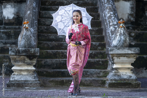 Beautiful Asian woman tourist wearing traditional Thai dress costume. The travel destination is ancient Phra Yuen Temple famous place of tourist attraction in Lamphun, Thailand. Fashion portrait.