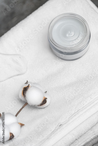 White terry towel next to the cream. Body towel.