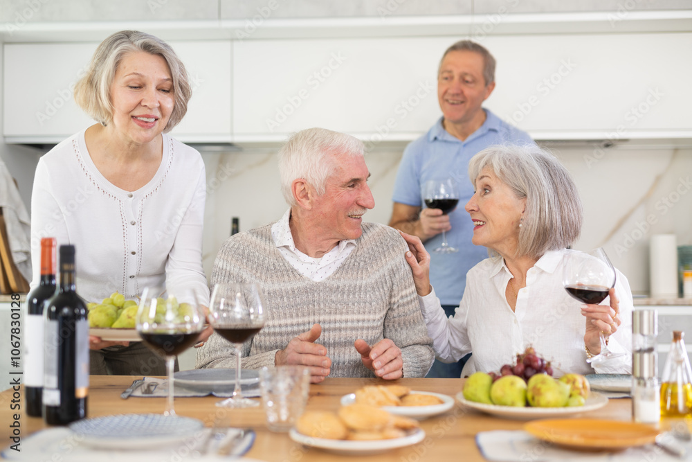 Group of happy elderly people drink red wine and chat at festive table Group of happy elderly people drink red wine and chat at festive table