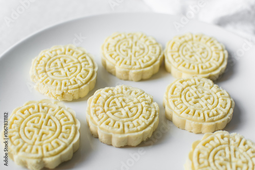 Overhead view of tuwon madara on a white plate, nigerian alawar madara milk candy, top view of milk fudge on a white ceramic plate