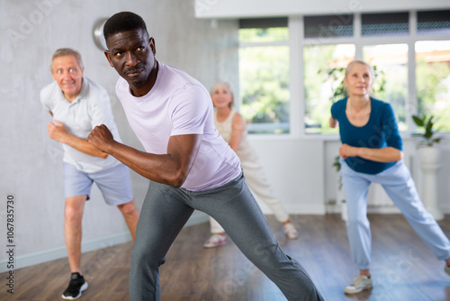 Group of multinational sports aged people rehearsing hip hop dance in dance hall photo