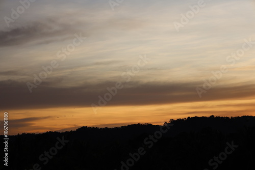 low hanging blue dark gray clouds hang low above rain forest covered hills as sunrise approaches photo