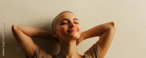 Woman with a joyful expression, hands behind her head, shaved head, lighttoned background, serene and uplifting atmosphere photo