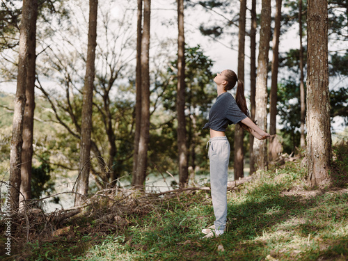 Young woman enjoying nature, standing among trees with arms outstretched, experiencing freedom and tranquility Connection with nature concept