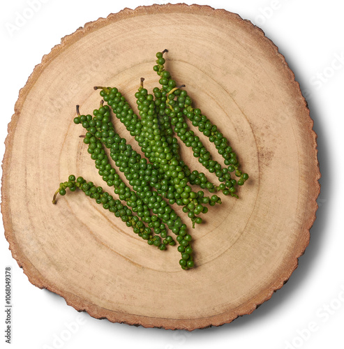 maturing black peppercorns on wooden tray isolated white background, young herbal spice with peppery heat taken straight from above