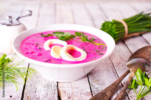 Cold beetroot soup in bowl on wooden background photo