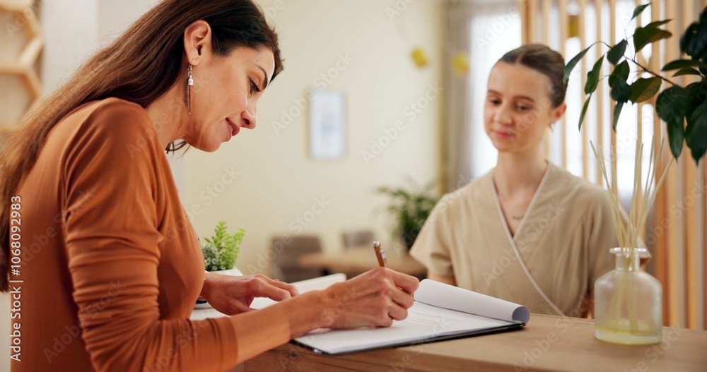 Salon, woman and client at reception with check in, paperwork and booking for luxury service at hotel. Sign up, registration and receptionist at front desk with customer information at beauty spa. Salon, woman and client at reception with check in, paperwork and booking for luxury service at hotel. Sign up, registration and receptionist at front desk with customer information at beauty spa.