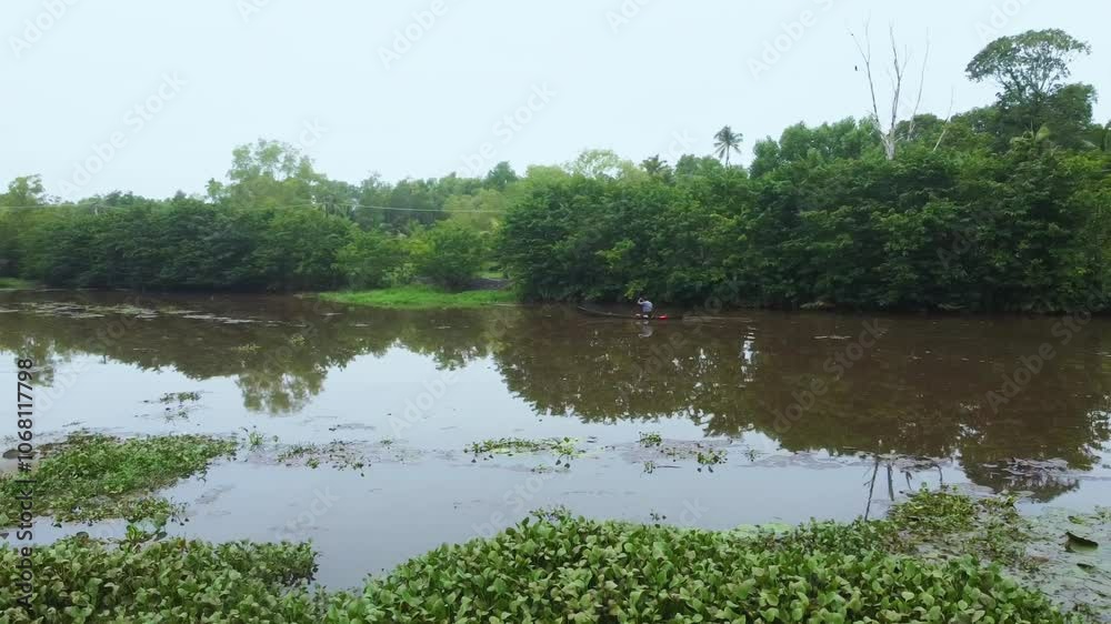 Traditional fishing in Kerala, India. The man goes fishing in a small boat, Algae can also be seen growing in the stream Traditional fishing in Kerala, India. The man goes fishing in a small boat, Algae can also be seen growing in the stream