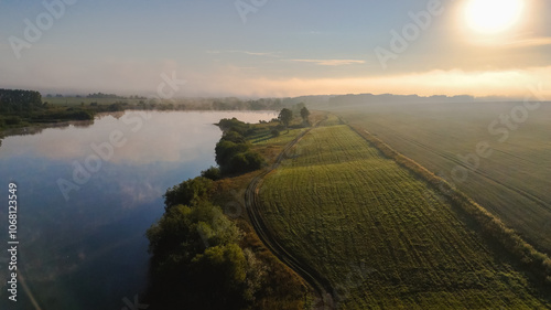 Dawn over the lake in the fog among the wheat fields