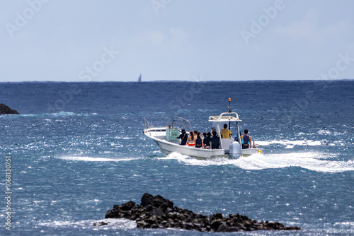 ヒリゾ浜渡船の漁船に乗って、海に出るスキンダイバー、シュノーケラーたち。 ヒリゾ浜の青い海と無人島の大根島、数多くの岩礁が見えている。 静岡県伊豆半島賀茂郡南伊豆町中木ヒリゾ浜2024年 