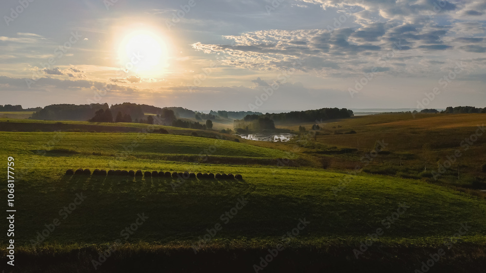 Obraz premium dawn over a green hilly meadow