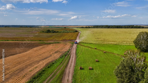 Wallpaper Mural The truck is driving along a dusty country road through green fields with rolls of hay Torontodigital.ca