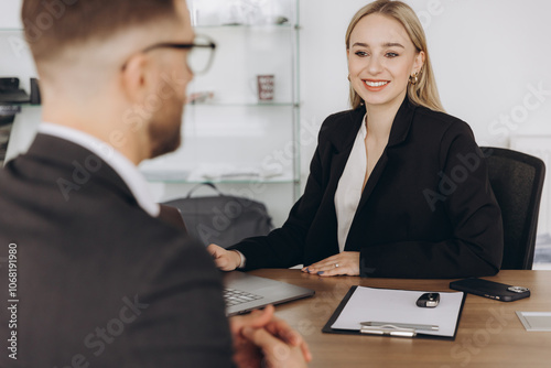 Smiling happy female manager car salesman in car dealership signing contract at table with male buyer in suit