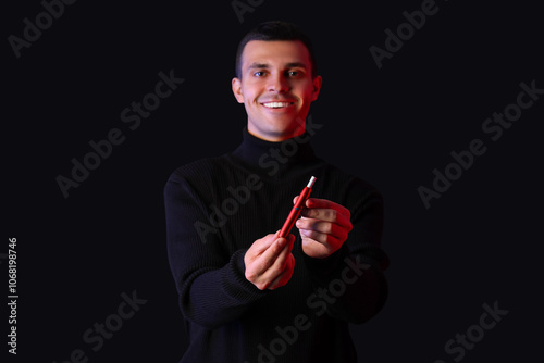 Young man with electronic cigarette on black background