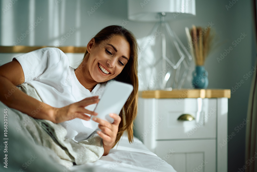 Happy woman in pyjama using smart phone while relaxing on bed at home. Happy woman in pyjama using smart phone while relaxing on bed at home.