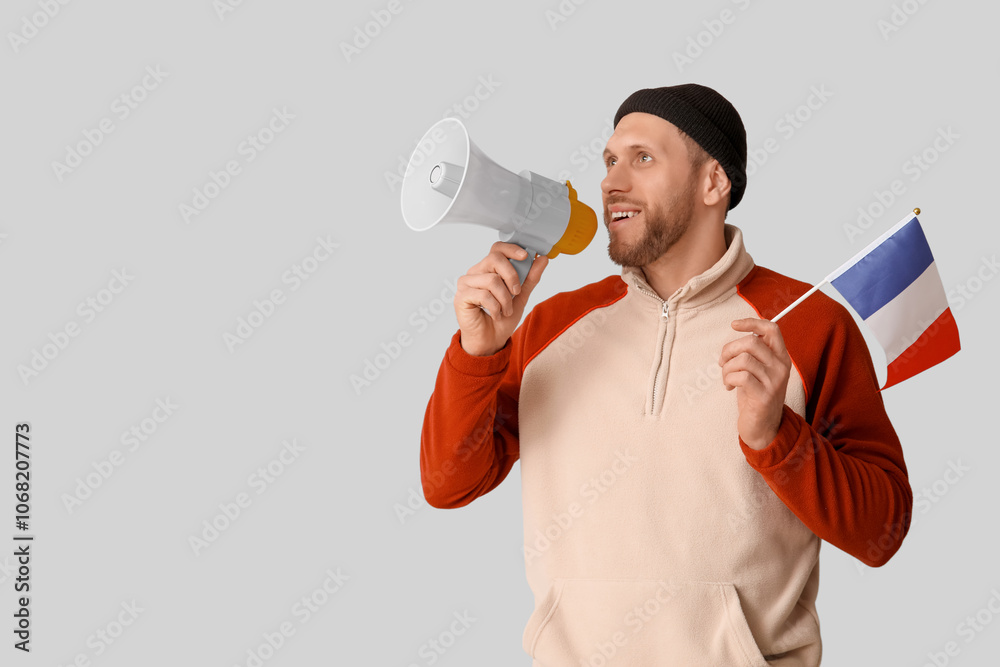 Young man with flag of France and megaphone on light background Young man with flag of France and megaphone on light background