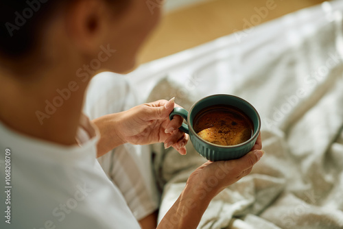 Фотография Close up of woman enjoying in morning coffee in bedroom.