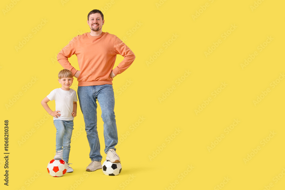 Fototapeta premium Young father and little son with soccer balls on yellow background