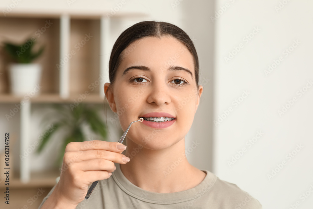 Beautiful young woman with dental braces and tool at home Beautiful young woman with dental braces and tool at home