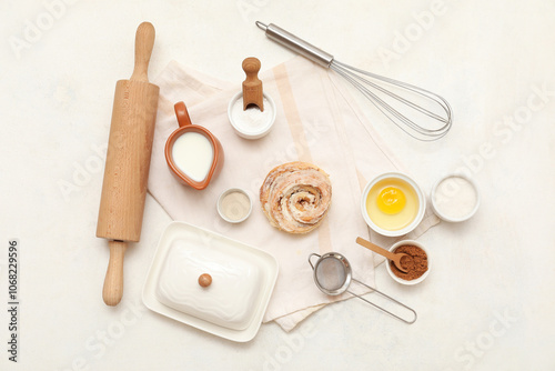 Sweet cinnamon roll and different ingredients on white background photo