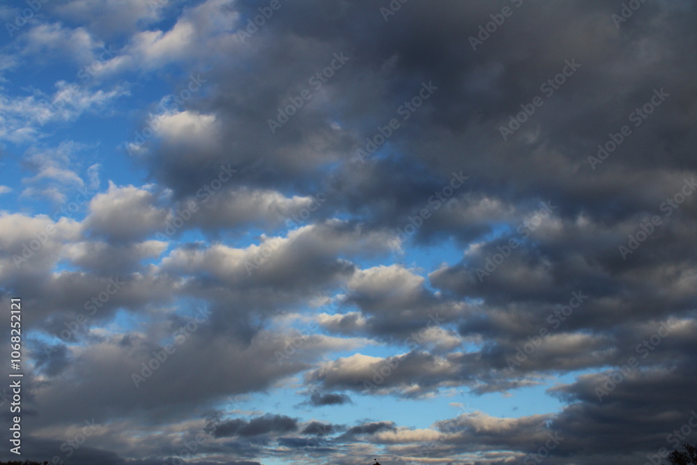 Obraz premium Dark and white clouds create a contrasting pattern against the blue sky.