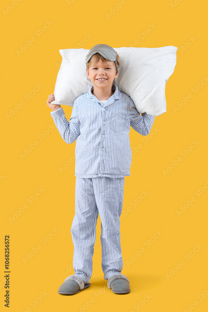Cute little happy boy in pajamas with sleeping mask and pillow on yellow background Cute little happy boy in pajamas with sleeping mask and pillow on yellow background