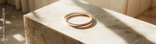 gold framed bracelet rests elegantly on marble surface, illuminated by soft sunlight. luxurious design and serene setting create sophisticated atmosphere