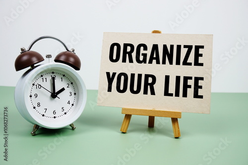 Organize Your Life text on paper card with alarm clock on green background photo