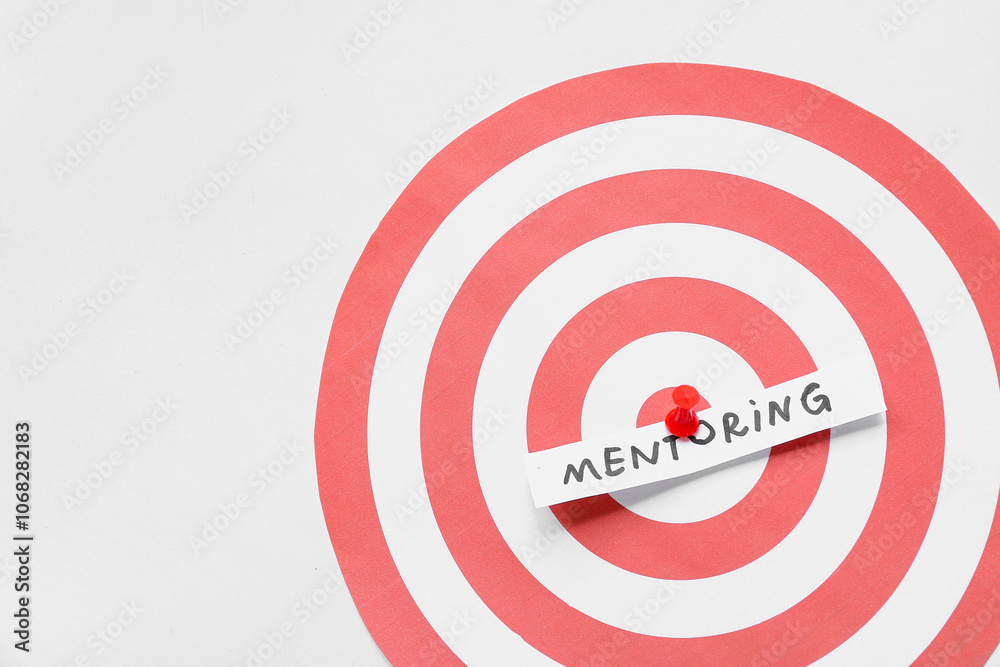 Paper with word MENTORING pinned on target, top view Paper with word MENTORING pinned on target, top view