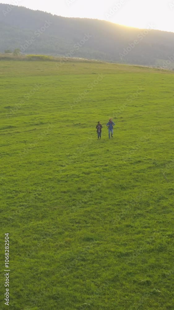 Aerial view of happy adventurous young couple tourists wearing backpacks and walking to the mountains. Hiking activity. Friendship. Romantic couple trip. Aerial view of happy adventurous young couple tourists wearing backpacks and walking to the mountains. Hiking activity. Friendship. Romantic couple trip.