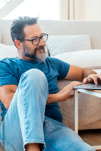 A man uses his laptop to navigate the internet in his apartment, either for work or leisure, enjoying the modern, comfortable environment with wireless connection in a relaxing space