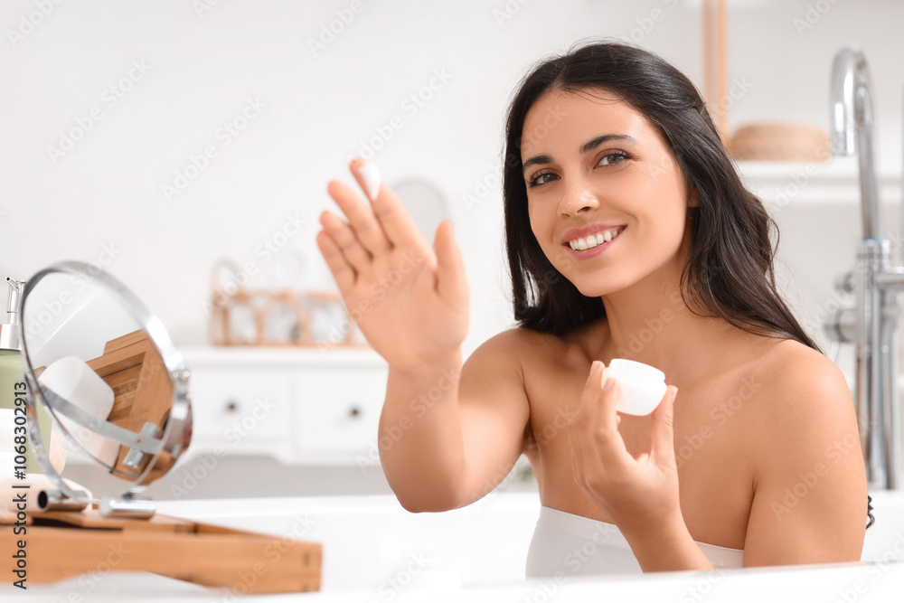 Beautiful young happy woman with mirror applying cream in bathtub at home Beautiful young happy woman with mirror applying cream in bathtub at home