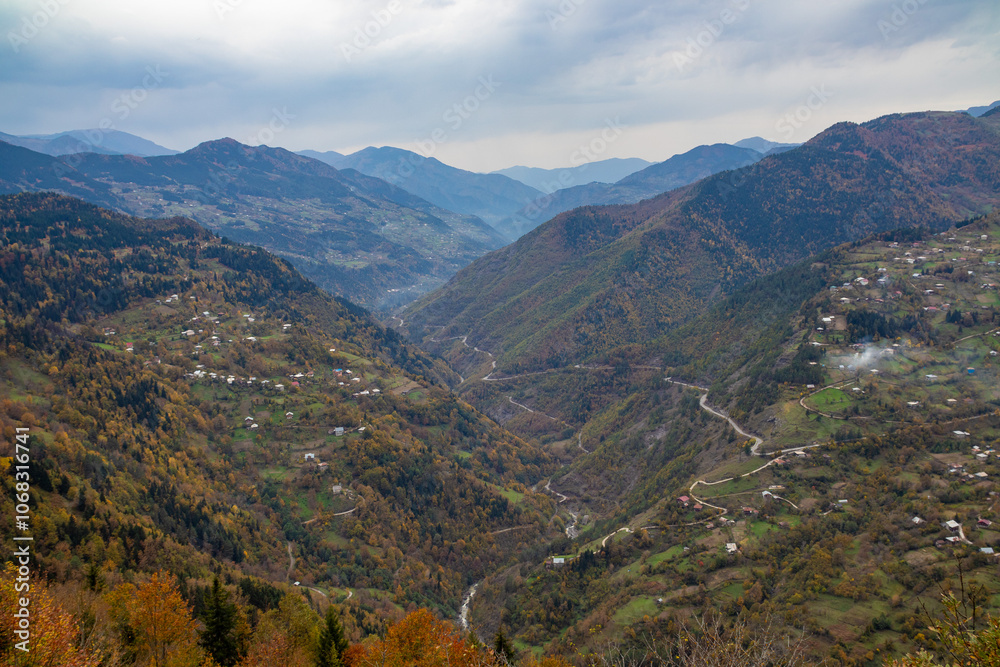 A serene valley surrounded by majestic mountains on a cloudy day A serene valley surrounded by majestic mountains on a cloudy day