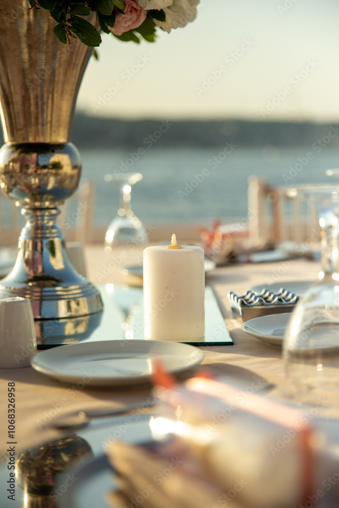 A romantic table setting with a silver vase, candles, and ocean view, perfect for wedding and event planners A romantic table setting with a silver vase, candles, and ocean view, perfect for wedding and event planners