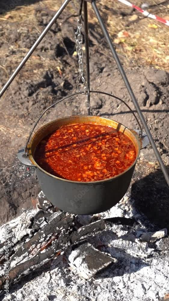 Cook red Ukrainian borscht over a campfire while hiking. Cooking food over a fire. Cauldron bowler pot. Camp picnic Cook red Ukrainian borscht over a campfire while hiking. Cooking food over a fire. Cauldron bowler pot. Camp picnic
