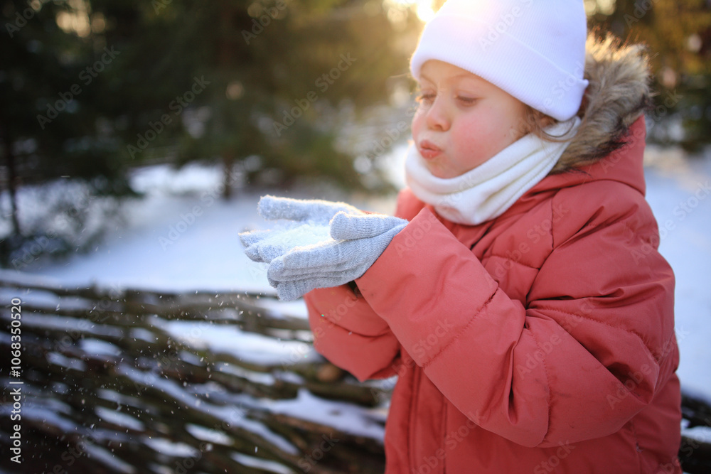 Obraz premium Winter Wonder: A Child Blowing Snowflakes from Their Hands