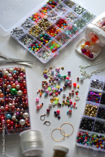 Colorful beads, letter beads, threads and other jewelry making supplies on white background. Making friendship bracelets concept. Selective focus.