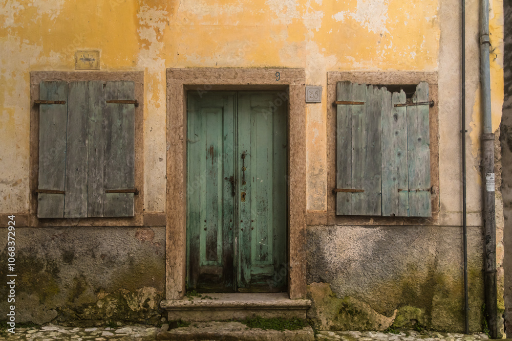 La facciata di una casa abbandonata con la porta e le finestre chiuse nel borgo di Erto, vicino alla diga del Vajont La facciata di una casa abbandonata con la porta e le finestre chiuse nel borgo di Erto, vicino alla diga del Vajont