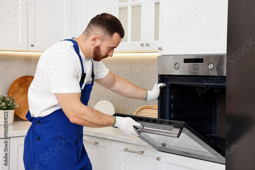 Repairman in uniform examining oven in kitchen