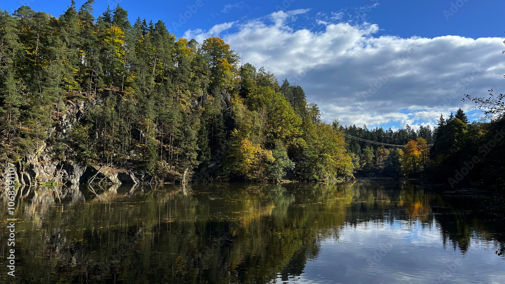 Autumn trees on rocks reflect off the surface of the river with floating autumn leaves. Poland Autumn trees on rocks reflect off the surface of the river with floating autumn leaves. Poland