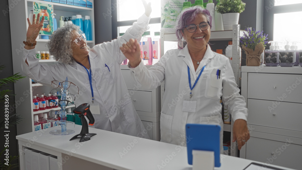 Obraz premium Middle-aged women dancing joyfully in a pharmacy shop while wearing lab coats, indicating a lively and fun moment during their work together as pharmacists in the drugstore interior
