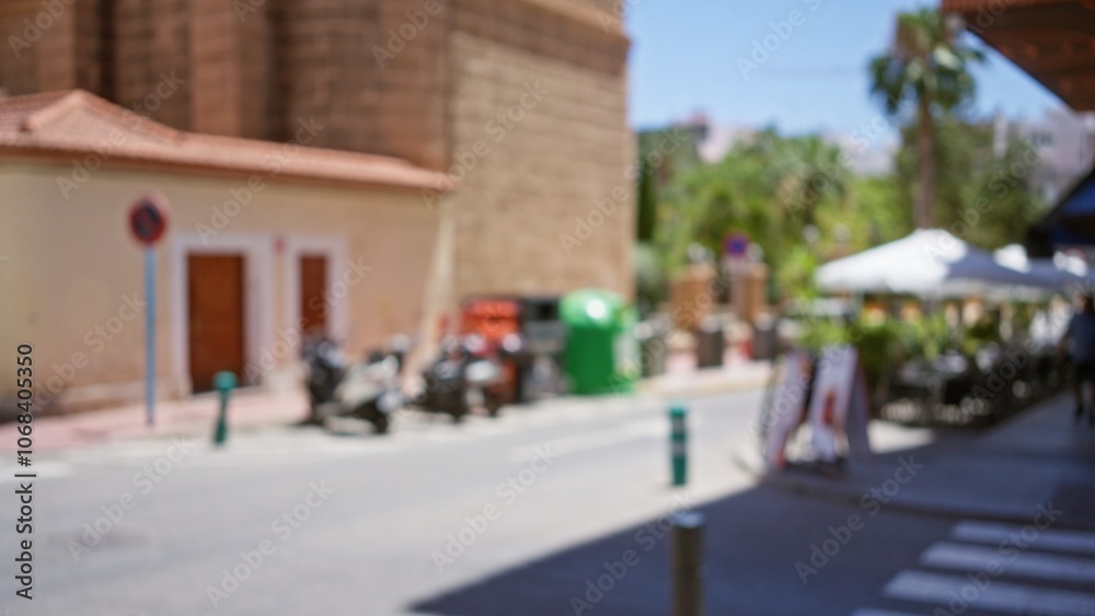 Blurred outdoor street scene with motorcycles, buildings, and defocused people under umbrellas in a bright, sunny day Blurred outdoor street scene with motorcycles, buildings, and defocused people under umbrellas in a bright, sunny day