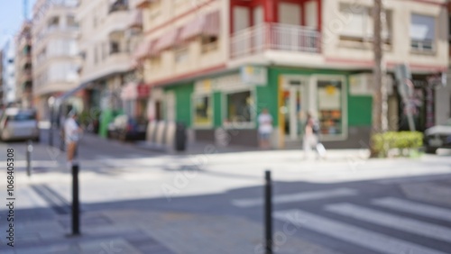 Blurred outdoor street scene with defocused buildings and people including man and woman walking on a sunny day with vibrant colors