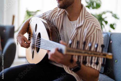 man’s hand skillfully strumming the strings of an oud, capturing the intricate design of the instrument and highlighting the delicate craftsmanship and cultural significance of the musical tradition.