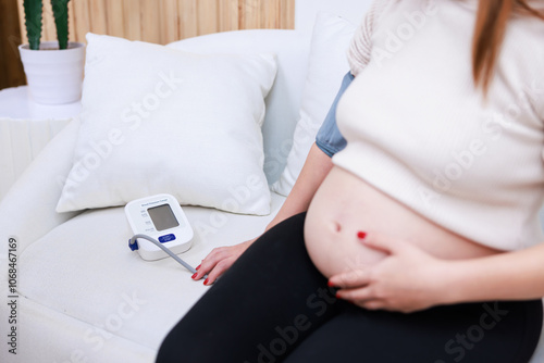 Pregnant woman measures blood pressure with sphygmomanometer equipment.