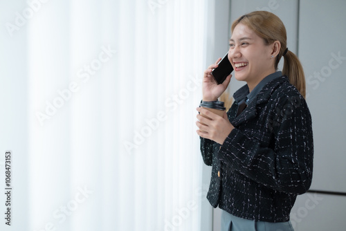 A woman is talking on her cell phone while holding a cup of coffee