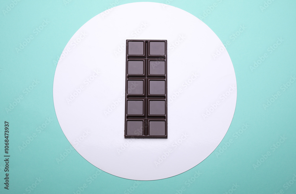 Dark chocolate bar on a blue background with white round Dark chocolate bar on a blue background with white round