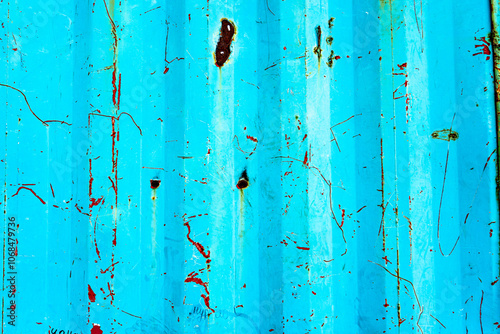 Close-up shot of a blue metal surface with a weathered, scratched, and rusted texture. The vibrant blue color contrasts with the rusty marks, creating a visually interesting, abstract background