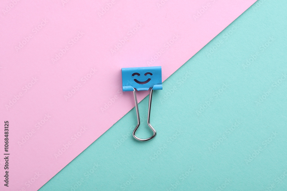 Binder clip with a smiling face on a pink blue background Binder clip with a smiling face on a pink blue background